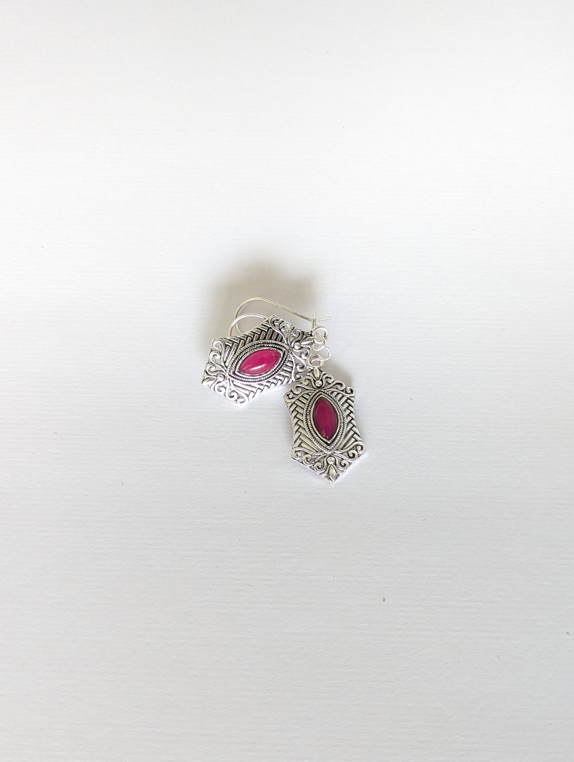 Silver earrings with pink gemstones on a white background