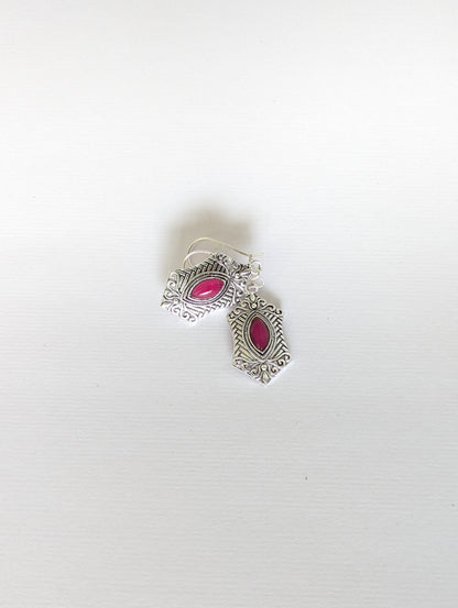 Silver earrings with pink gemstones on a white background
